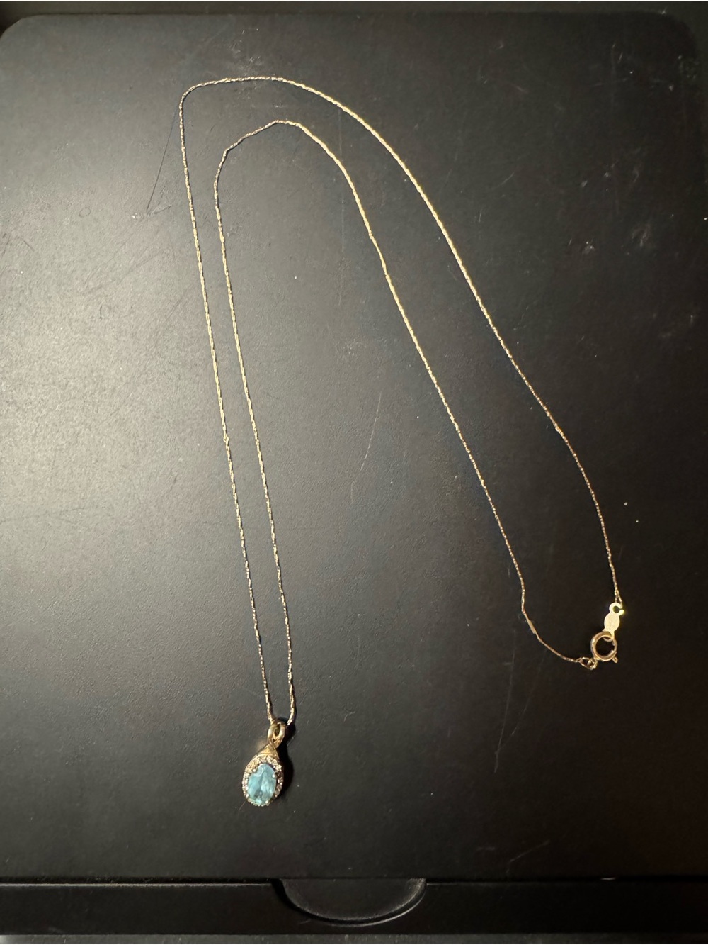 Oval Swiss Blue Topaz and 1/15 CT. T.W. Diamond Frame Pendant in 10K Gold